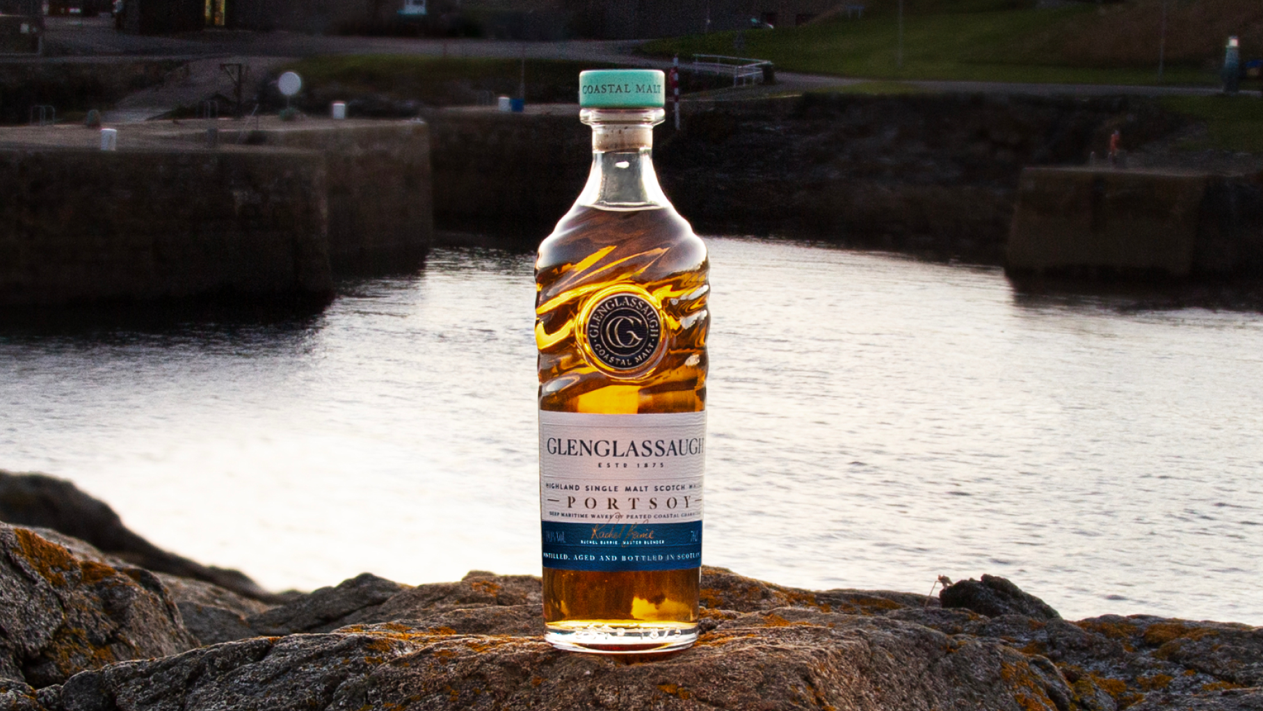 Bottle of Portsoy Glenglassaugh and the distillery behind it.